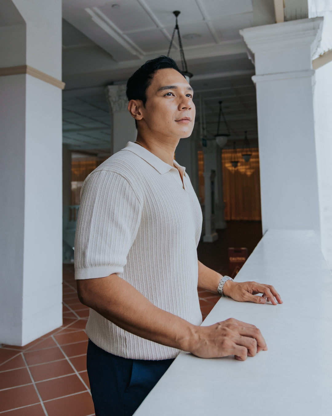 Man leaning on a counter in an indoor setting wearing clothes for short men