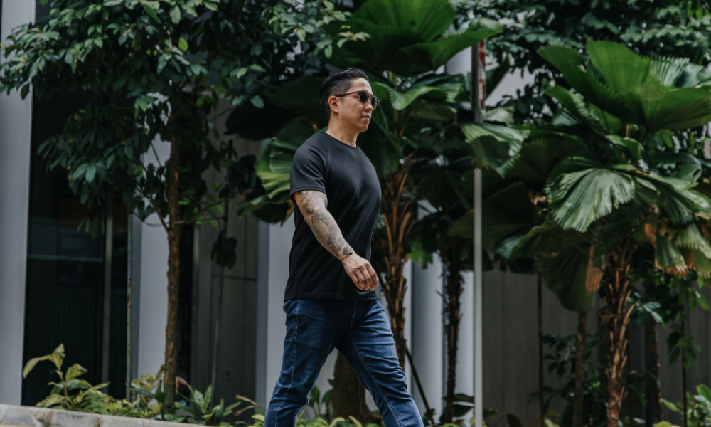 Man walking outdoors with greenery in the background wearing t-shirts for short men