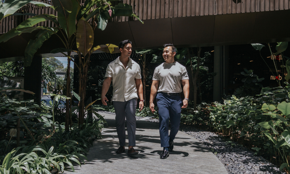 Two men walking along a path in a garden setting wearing pants for men 175cm & under
